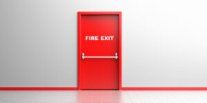 A closed red Boon Woh fire rated door in Singapore with white text, push bar, and a light-colored wall and floor.
